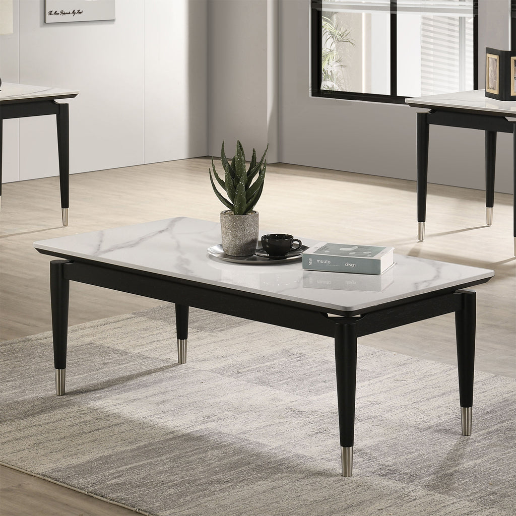 Contemporary coffee table with sintered stone top in black and white, featuring silver-capped tapered legs, styled in a modern living room.