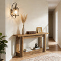 Rustic oak 2-tier console table featuring thick column legs, styled with a vase, vintage box, and books in a hallway.