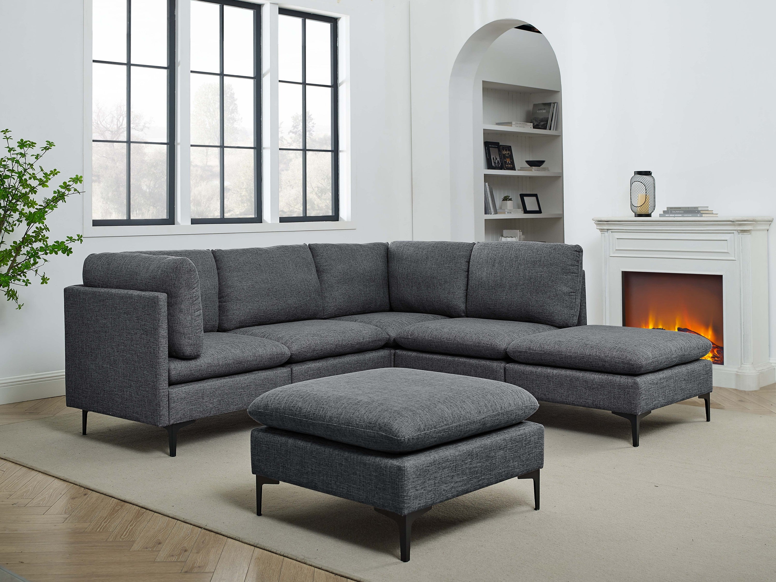 Charcoal grey linen modular sectional with a matching ottoman, featuring clean lines and slender black metal legs.