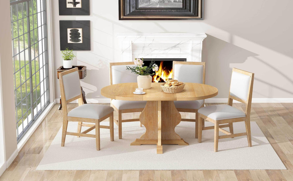 Elegant farmhouse dining set with round wood table and four upholstered chairs placed on a cream rug in a cozy room setting.