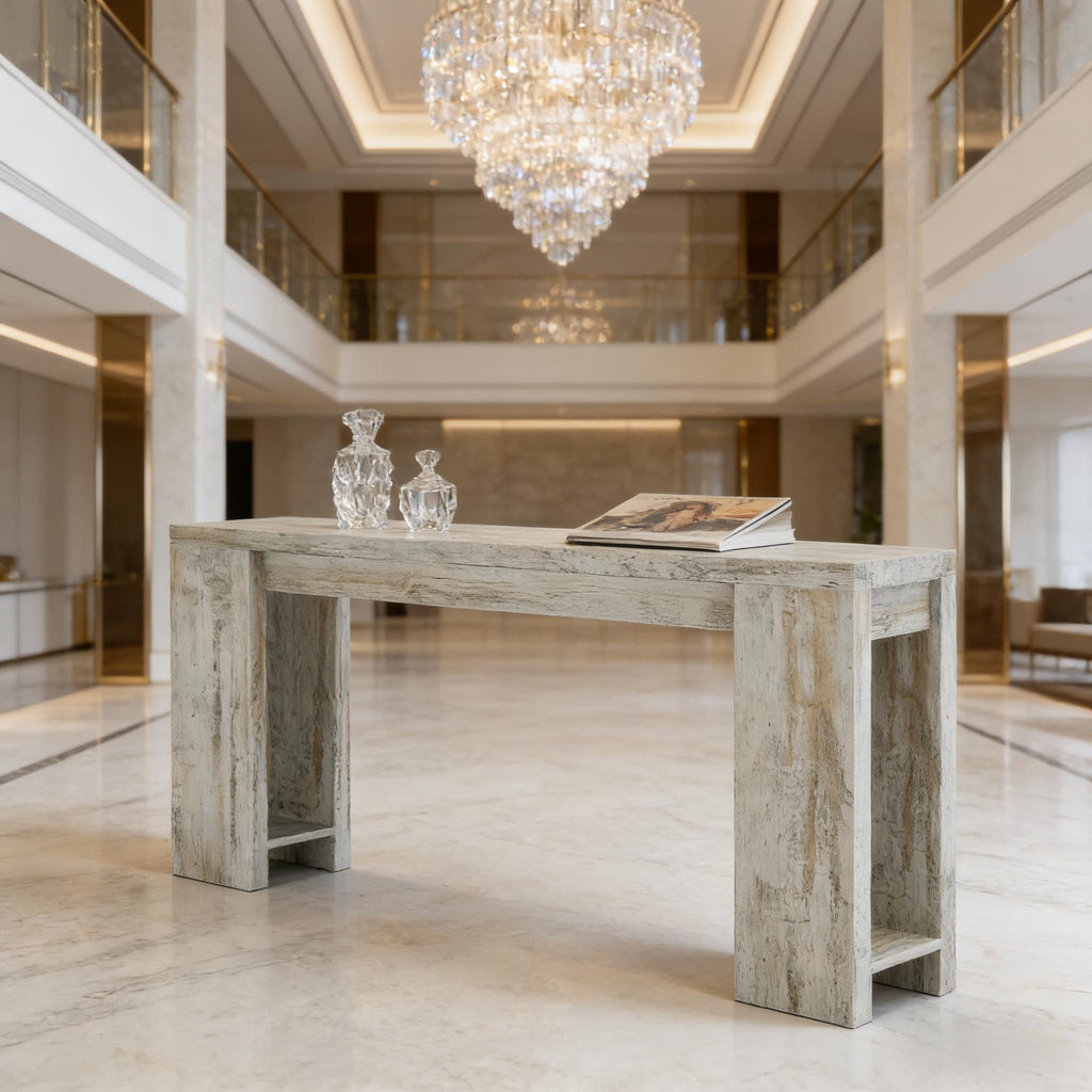 Rustic white-washed wooden console table with wide, open legs, set in a luxurious, grand foyer.