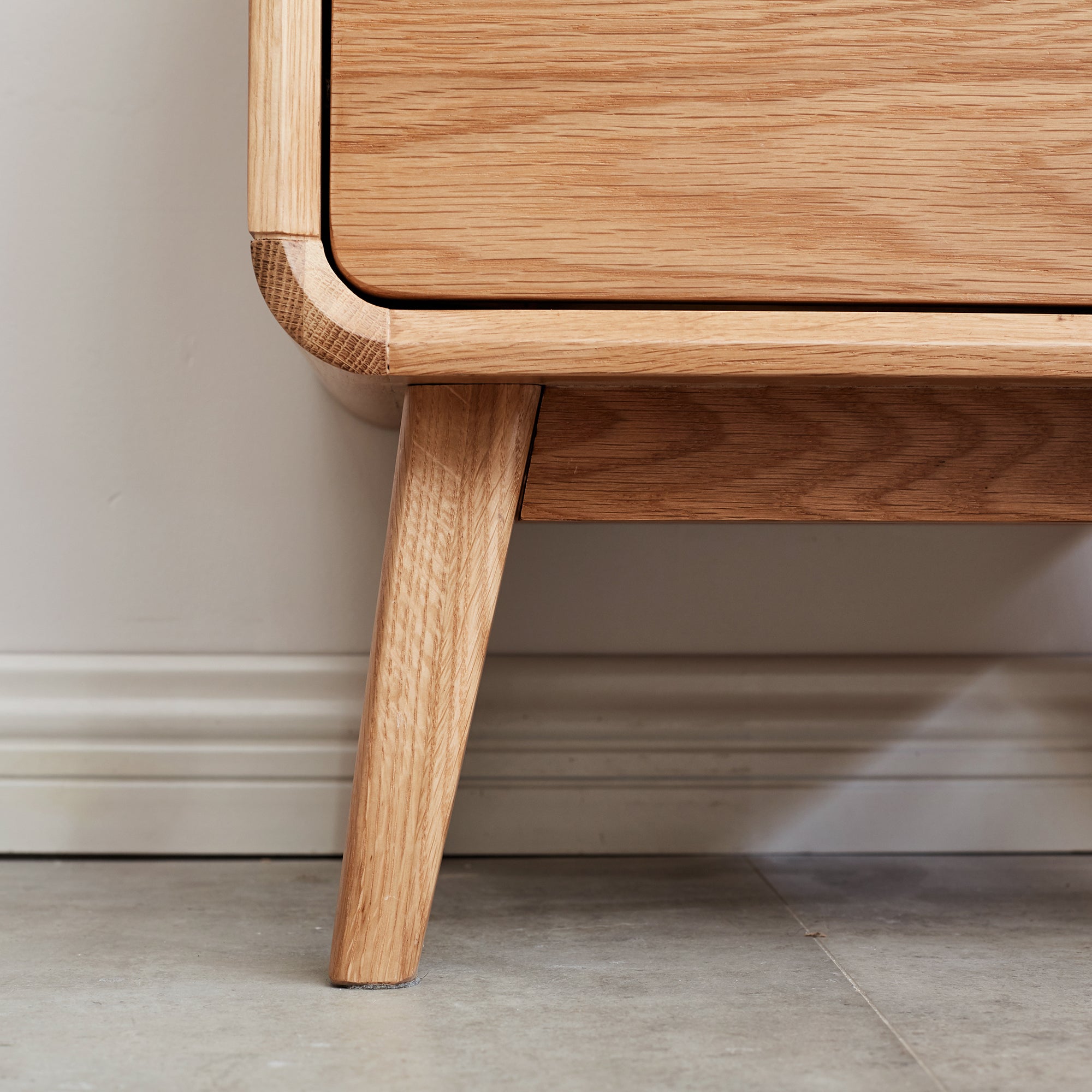 Solid Wood Bedside Cabinet - Organized Storage showing close-up of tapered oak leg and smooth corner detailing.