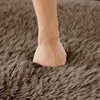 Hand pressing into plush chocolate fabric of L-shaped modular sofa. Demonstrates softness and high-density cushioning for ergonomic support.