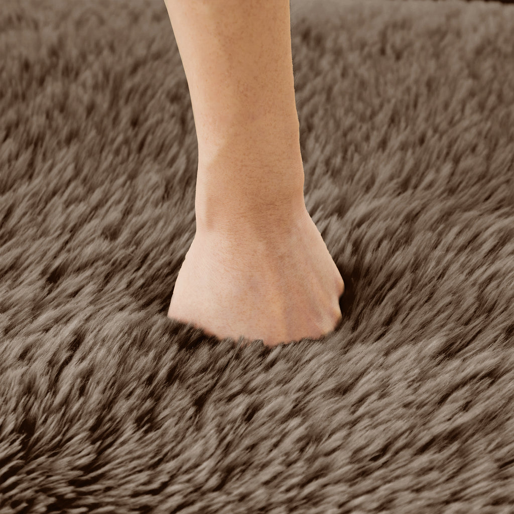 Hand pressing into chocolate plush fabric of modular sofa, demonstrating soft, high-density cushioning and premium texture.