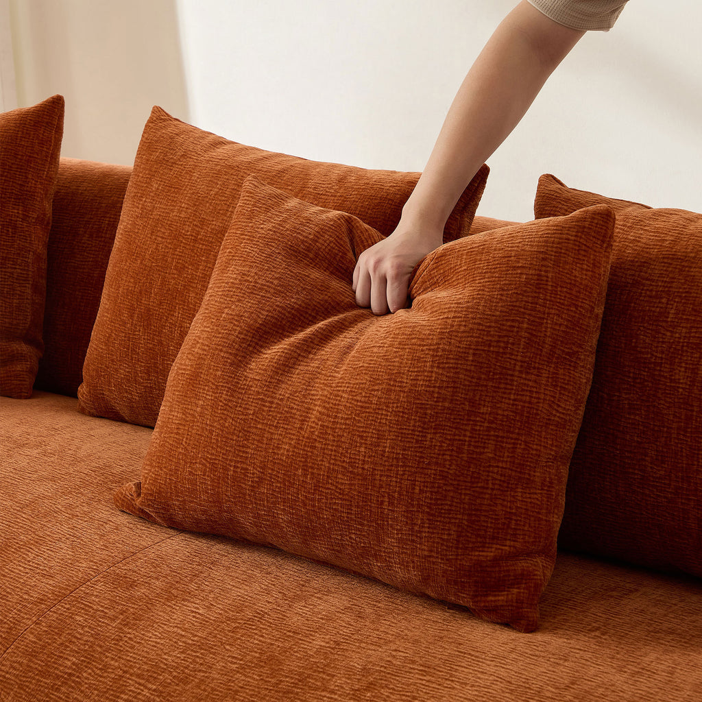 Close-up of hand pressing into plush back cushion of modern L-shape sectional sofa, highlighting soft and supportive comfort.