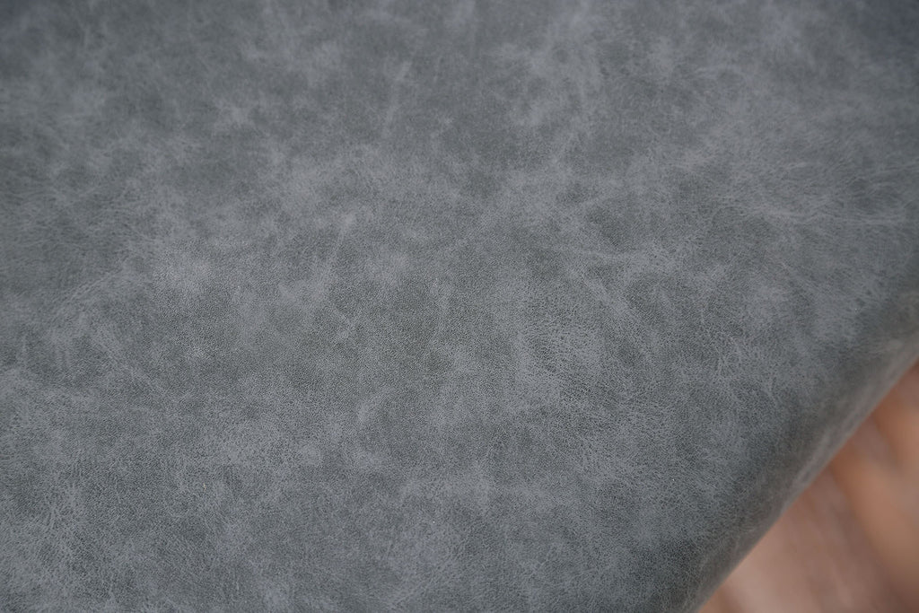 Detailed texture of the gray cushioned seat on minimalist dining chairs, highlighting soft, durable upholstery.