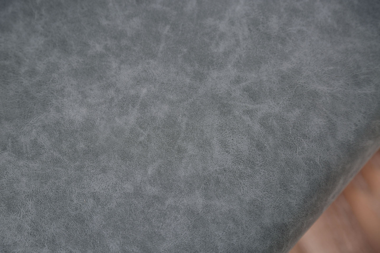 Detailed texture of the gray cushioned seat on minimalist dining chairs, highlighting soft, durable upholstery.