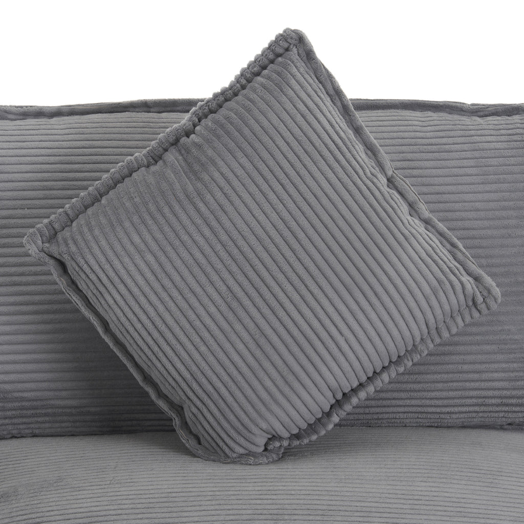 Detail of square cushion on dark grey modular sofa, featuring plush corduroy texture and piped edges for added style.