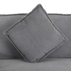 Detail of square cushion on dark grey modular sofa, featuring plush corduroy texture and piped edges for added style.
