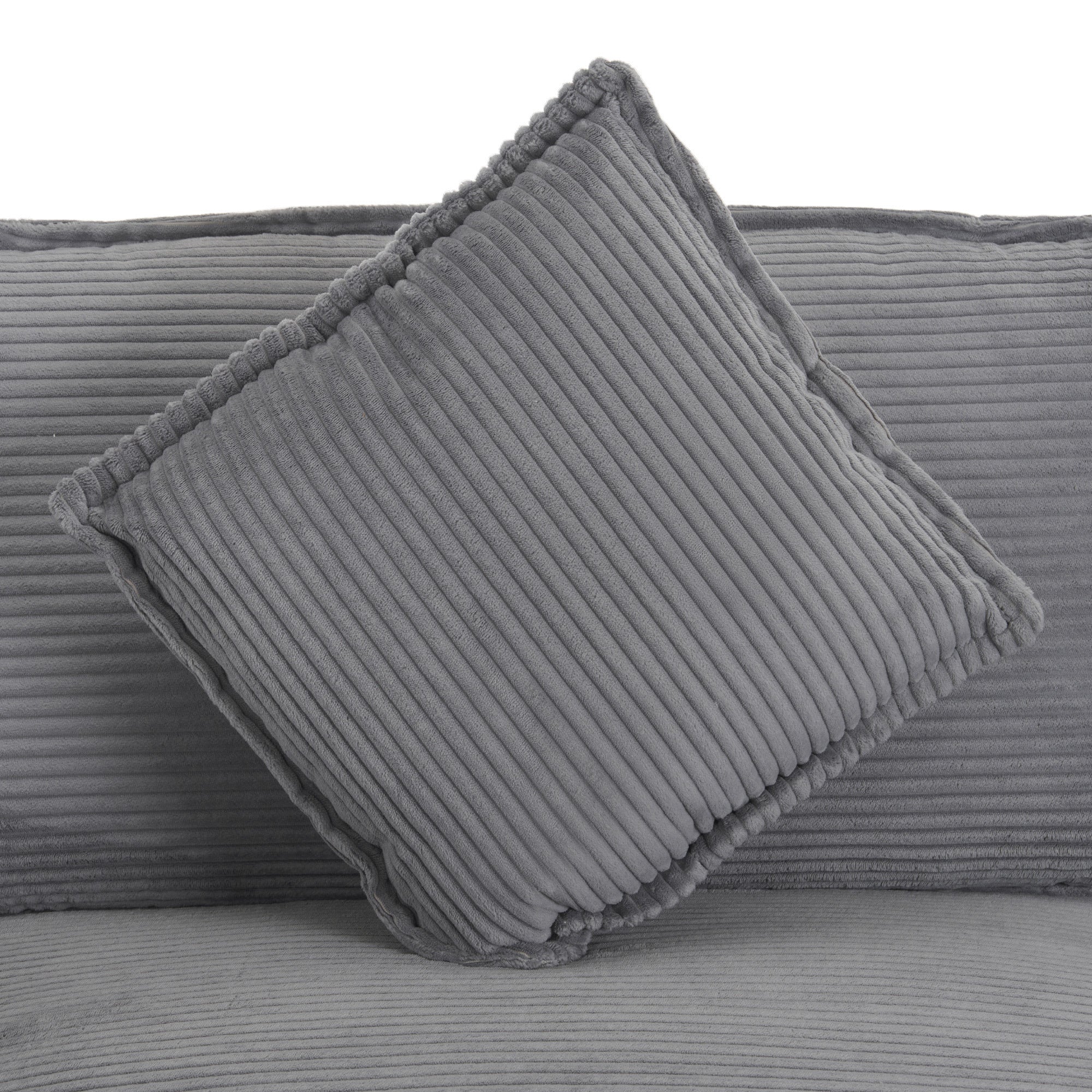 Detail of square cushion on dark grey modular sofa, featuring plush corduroy texture and piped edges for added style.