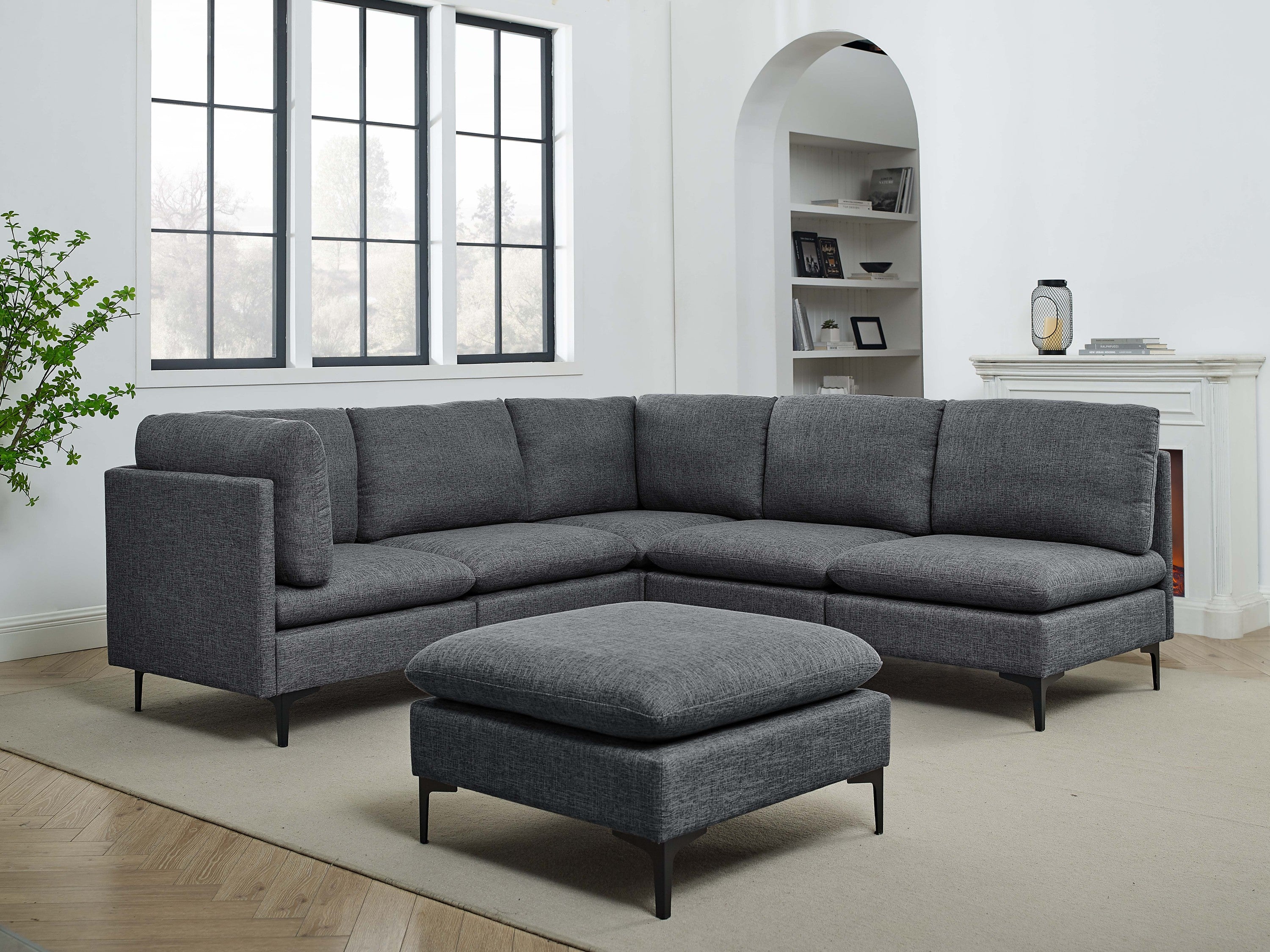 Modern charcoal grey linen modular sectional sofa with plush cushions and sleek black metal legs, including an ottoman.