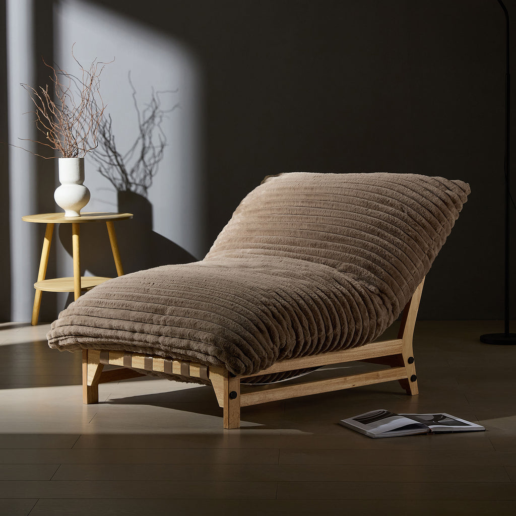 Corduroy lounge chair in moody lighting, emphasizing its plush ribbed cushion and natural wood frame for stylish comfort.