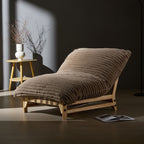 Corduroy lounge chair in moody lighting, emphasizing its plush ribbed cushion and natural wood frame for stylish comfort.