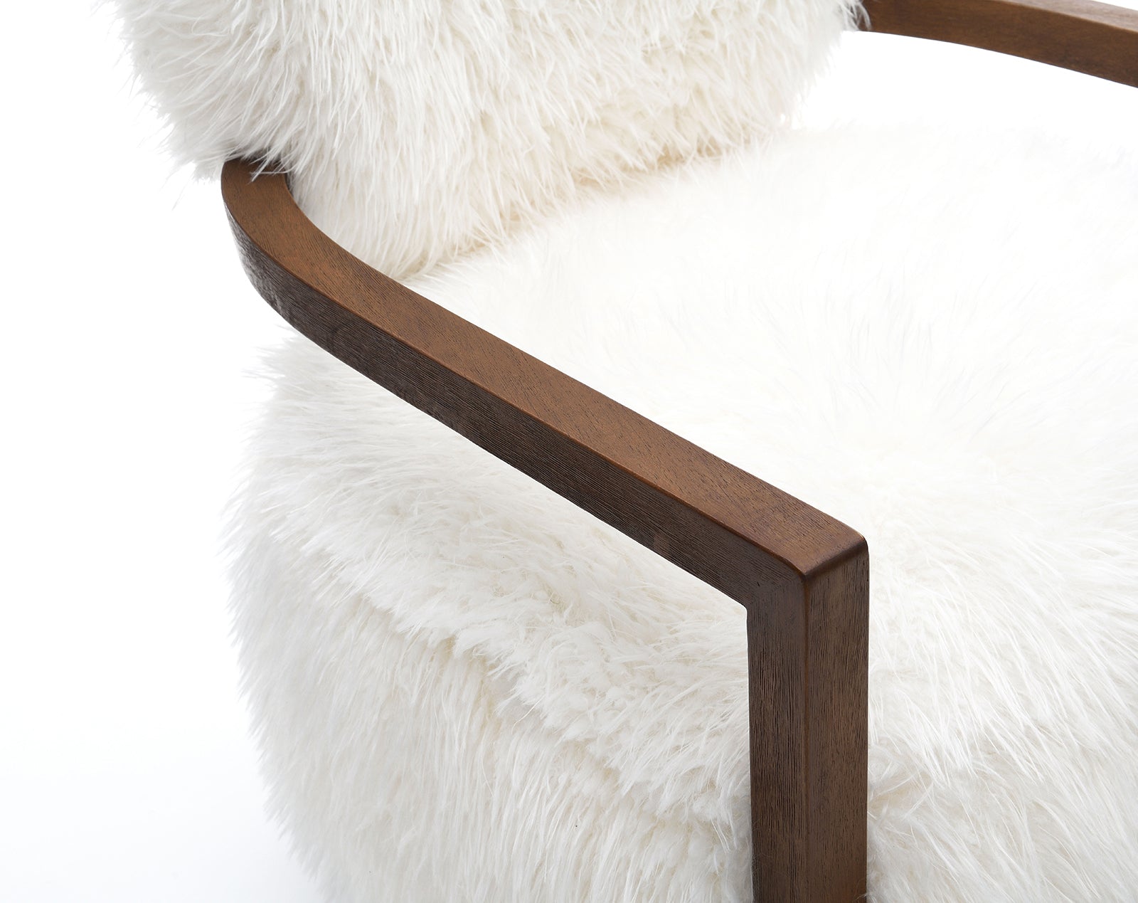 Detail view of the wooden armrest and fluffy faux fur seat of the white accent chair, emphasizing craftsmanship.