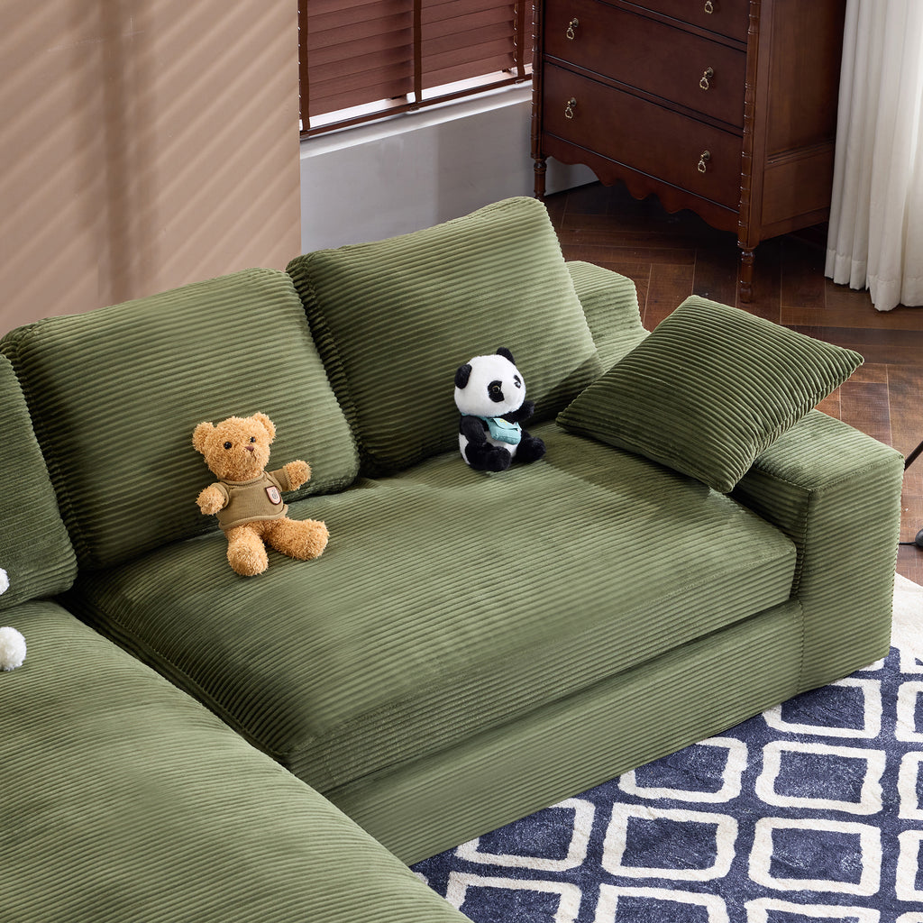 Green corduroy sofa with cushions and plush pillows, styled with teddy bears on a geometric rug, ideal for family-friendly interiors.