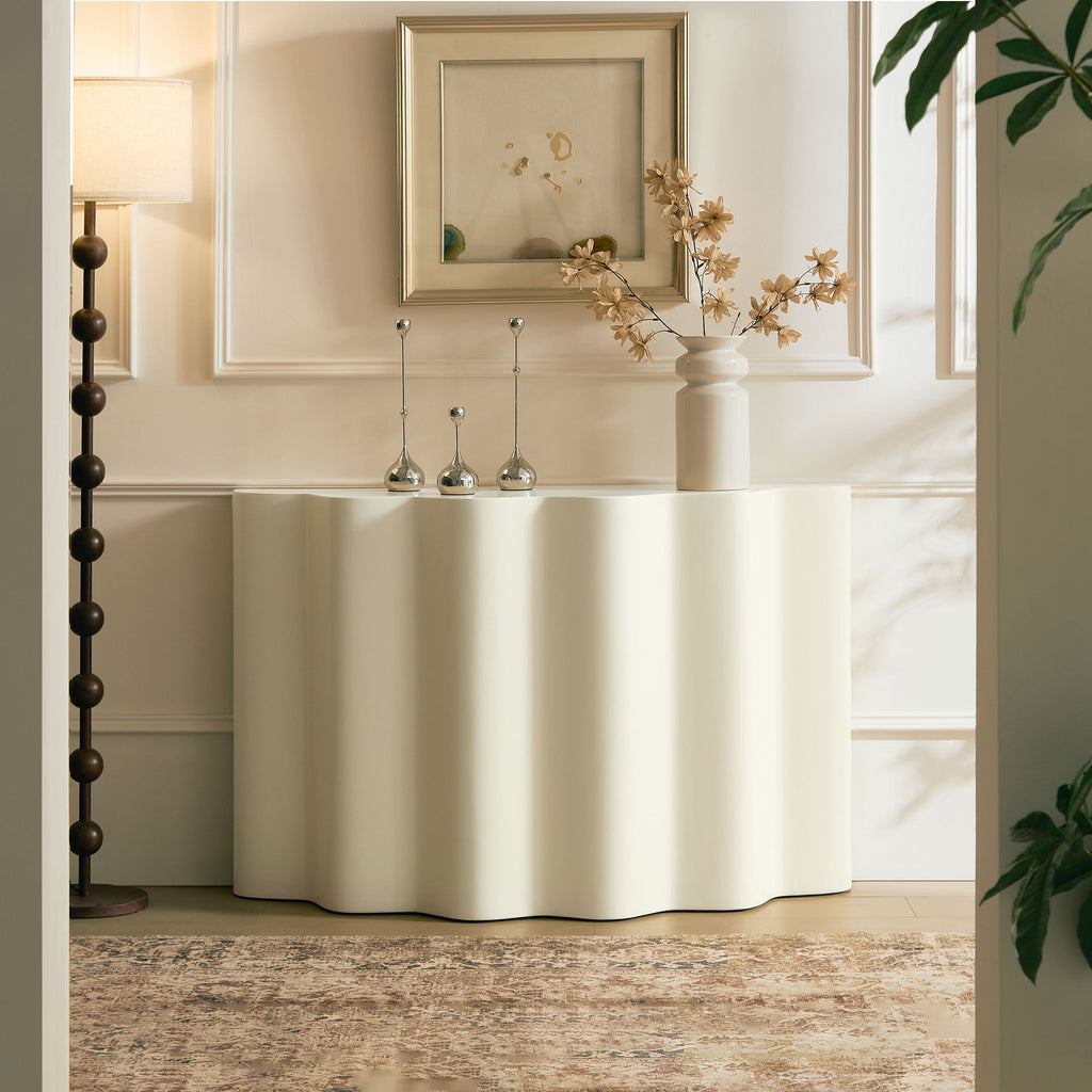 Modern white fiberglass console table with a wavy, sculptural design, styled in a minimalist entryway.