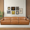Tan leather triple power recliner sofa with clean lines and integrated control buttons on arms in a modern setting.