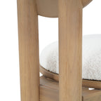 Close-up of chair's back leg joint and seat cushion, highlighting wood grain and fabric texture.