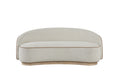 Curved beige tight-back sofa with brown piping detail on a light wood plinth base against a white background.