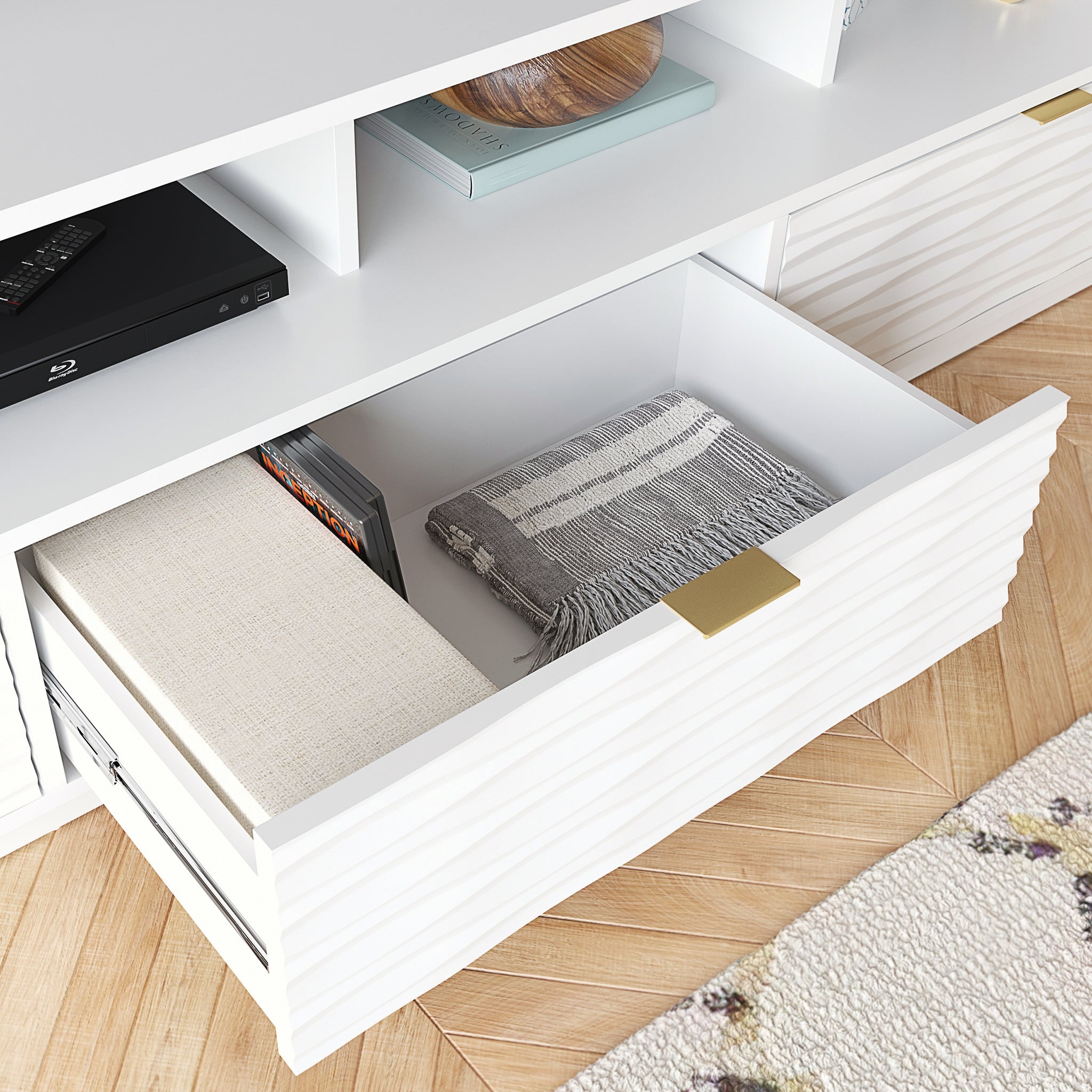 Close-up of open drawer in White Coastal Credenza, showing interior storage with folded blanket and books, ideal for living room use.