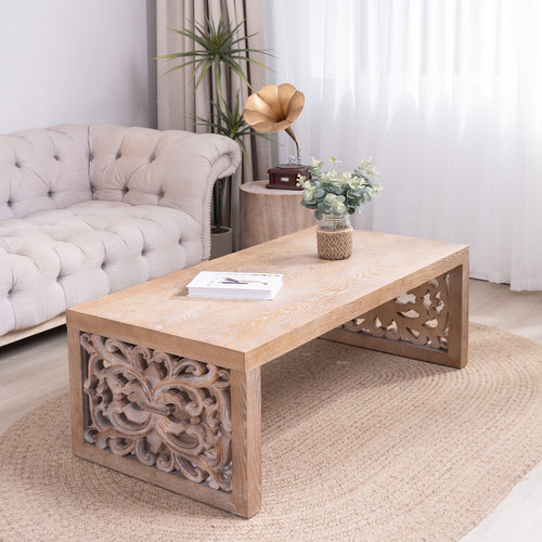 Rustic carved wood coffee table in a cozy living room, featuring ornate side panels and natural wood finish for a handcrafted aesthetic.