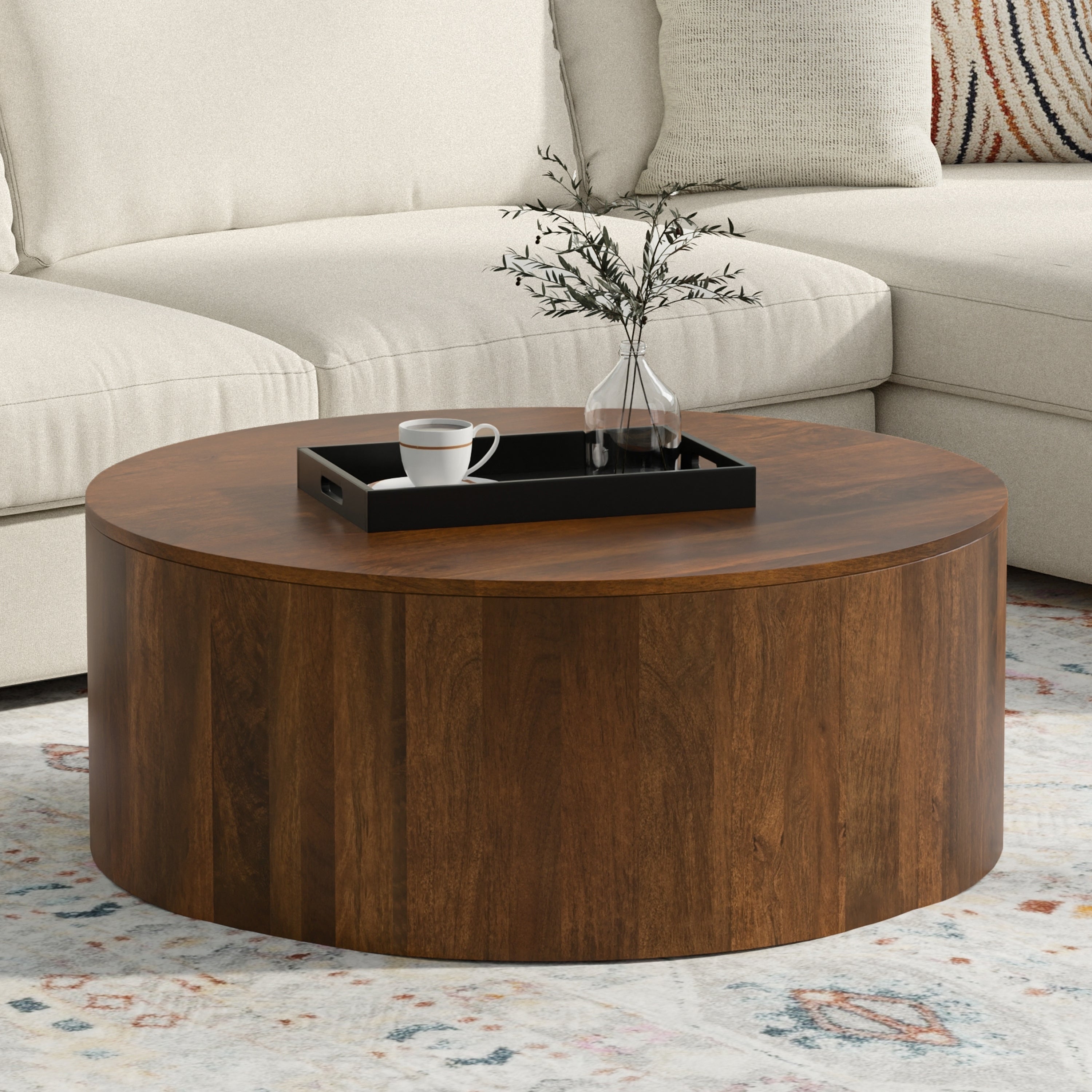 Millbury Drum Coffee Table in walnut brown placed in a modern living room with neutral sectional sofa and decorative tray on top.