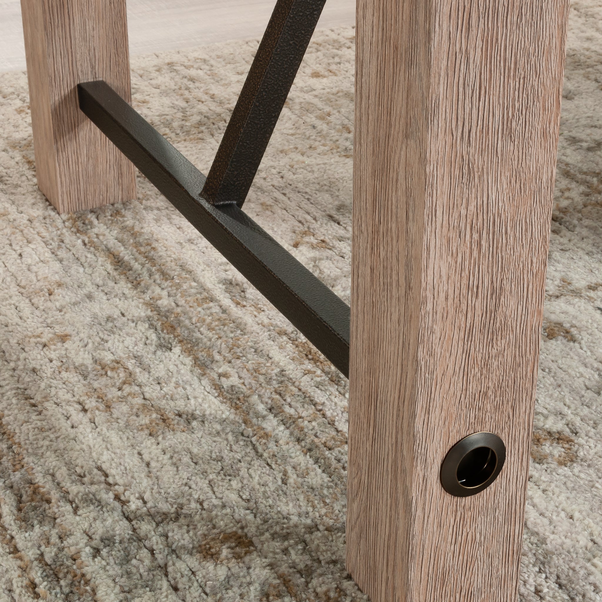 Close-up of brown finish desk leg with black metal support bar, showcasing rustic texture and sturdy construction.