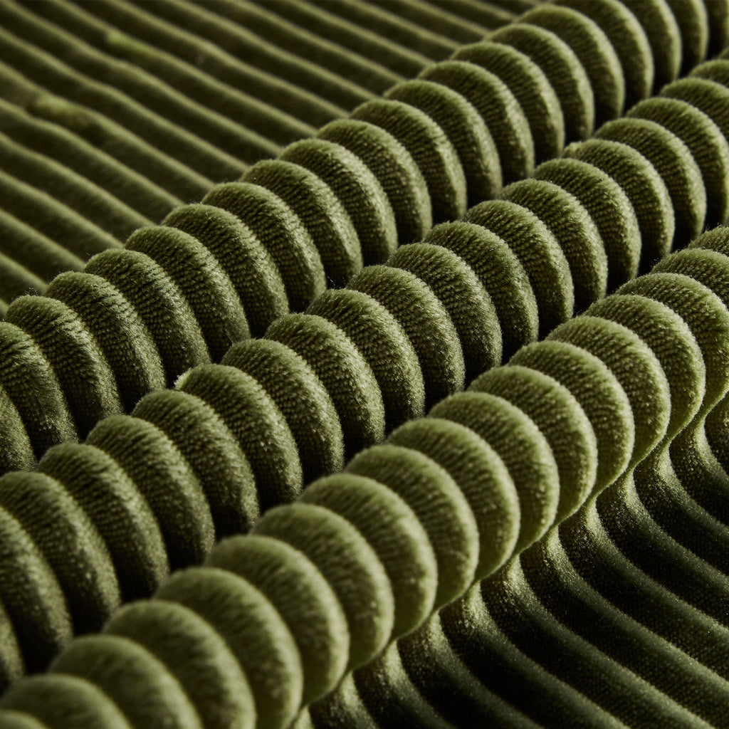 Close-up of green corduroy fabric texture with ribbed pattern. Soft, skin-friendly material ideal for comfortable seating.