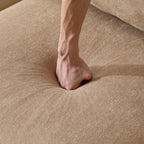 Hand pressing into the seat cushion of the 99 in. modular velvet sectional sofa, demonstrating softness and comfort.