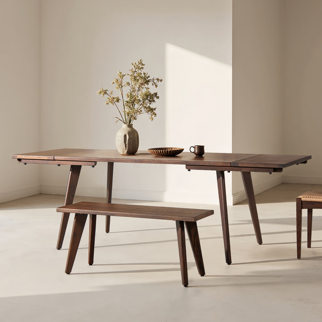 Capri 41.5' solid red oak wood bench in dark brown placed beside matching dining table in minimalist room. Ideal for kitchen or dining use.
