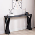 Sleek black console table with modern crossed legs design, placed in an entryway with books and vases for decor.