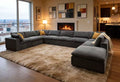Large, grey, U-shaped modular sectional sofa in a modern living room with yellow accent pillows and a plush beige rug.
