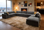 Large, grey, U-shaped modular sectional sofa in a modern living room with yellow accent pillows and a plush beige rug.