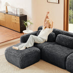 Woman relaxing on dark grey modular sectional sofa in plush fabric. Showcases comfort, ergonomic support, and setup-free design.
