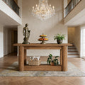 Solid wood 2-tier console table with chunky cylindrical legs, styled in a grand entryway with decor and a rug.