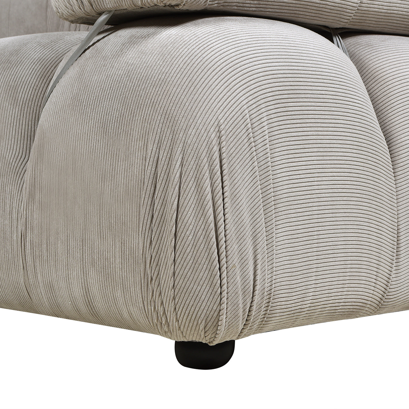Zoomed-in view of the lower side of the gray lounge arm chair, emphasizing the soft corduroy fabric and bubble-style padding.