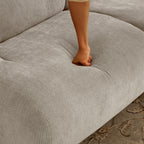Hand pressing into beige memory foam sofa cushion, highlighting the plush comfort and responsive support of the compact 2-seater.