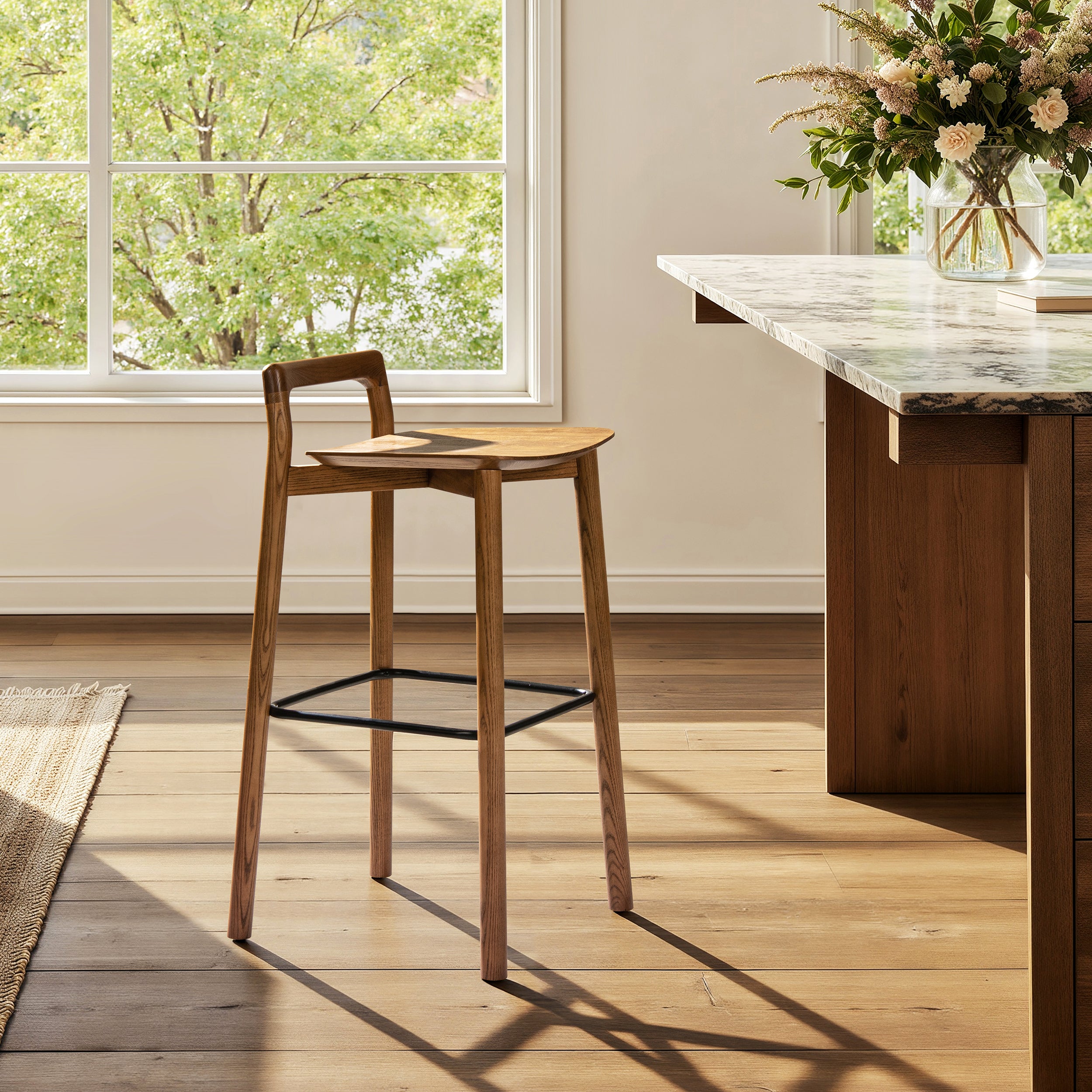 Single Sven 30' modern low back barstool in dark brown walnut ash wood near a marble kitchen island with natural light.
