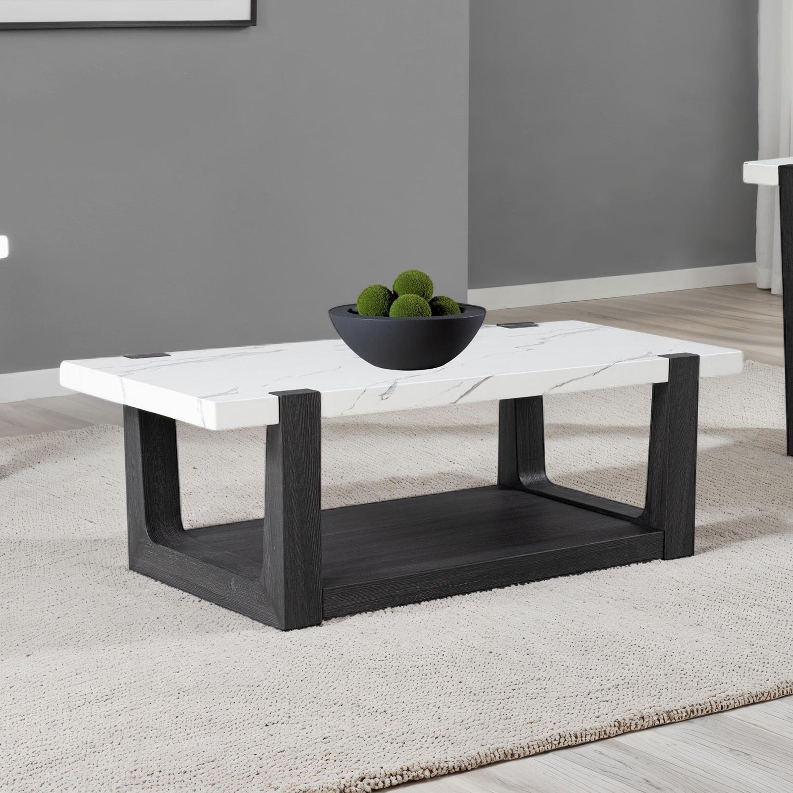 Modern coffee table with faux marble top and black wood base, placed on a beige rug in a contemporary living room setting.