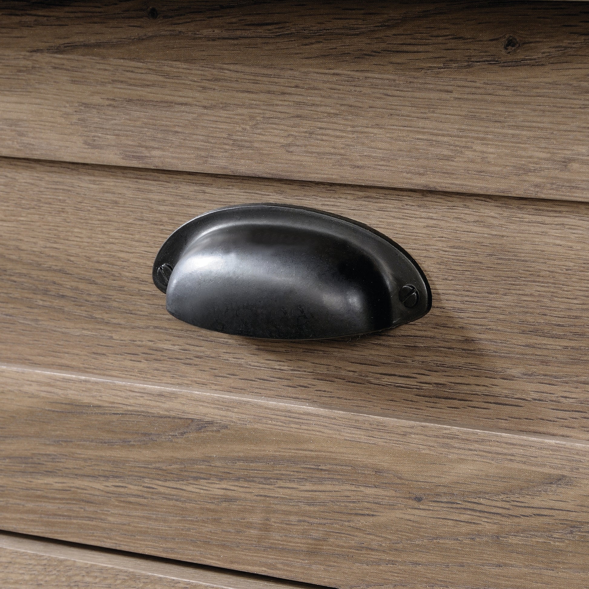Detailed view of a black metal cup handle on the brown dresser drawer, highlighting its rustic and functional design.