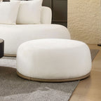 Close-up of the round beige ottoman included with the oversized L-shape sectional sofa, ideal for extra seating or footrest use.