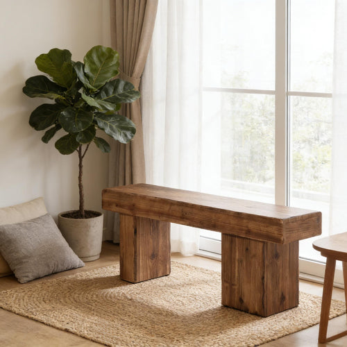 Rustic solid wood bench with a chunky, minimalist design and natural grain finish on a jute rug by a bright window.