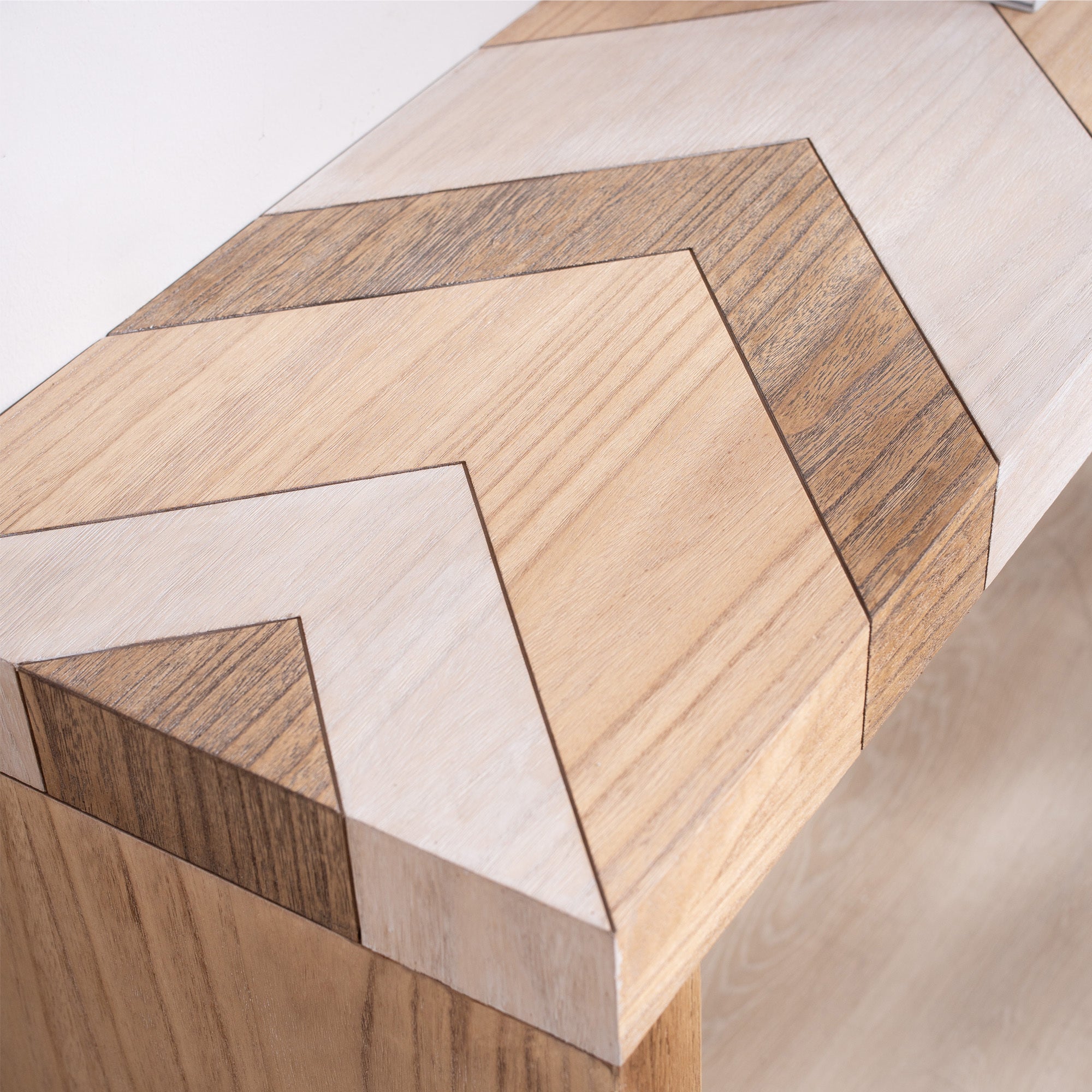 Close-up of chevron patterned tabletop on modern console table, highlighting detailed wood grain and craftsmanship.