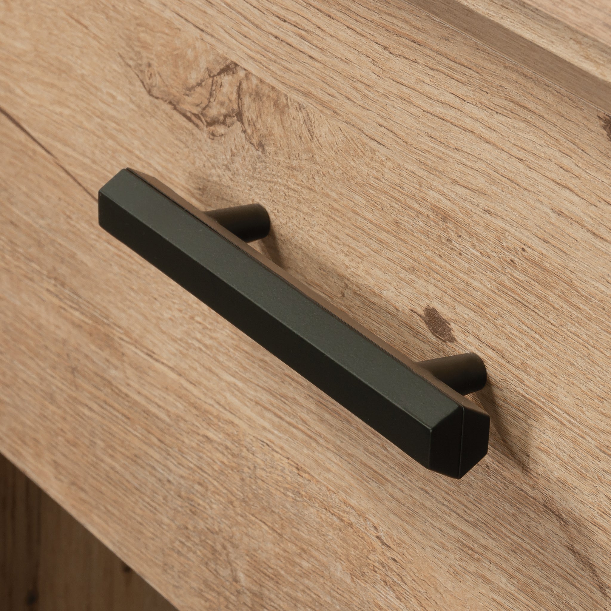Close-up of the night stand's black metal drawer handle contrasting with the brown wood finish for a modern rustic style.
