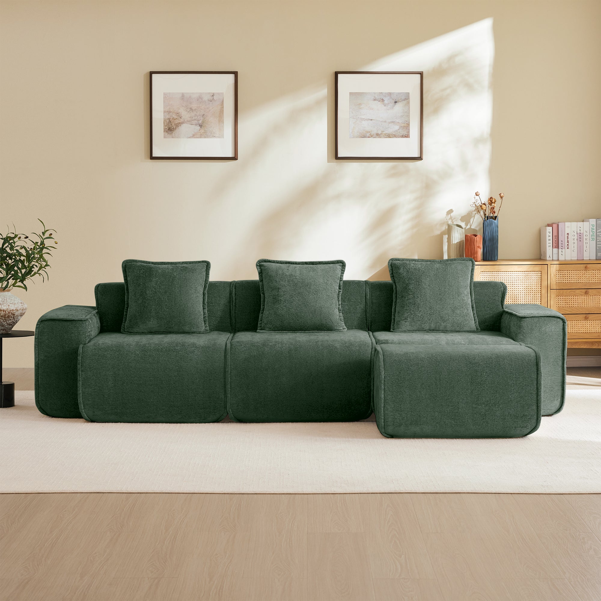 Green Modular Velvet Sectional Sofa with three seats and ottoman, styled against a beige wall with framed art and natural light.