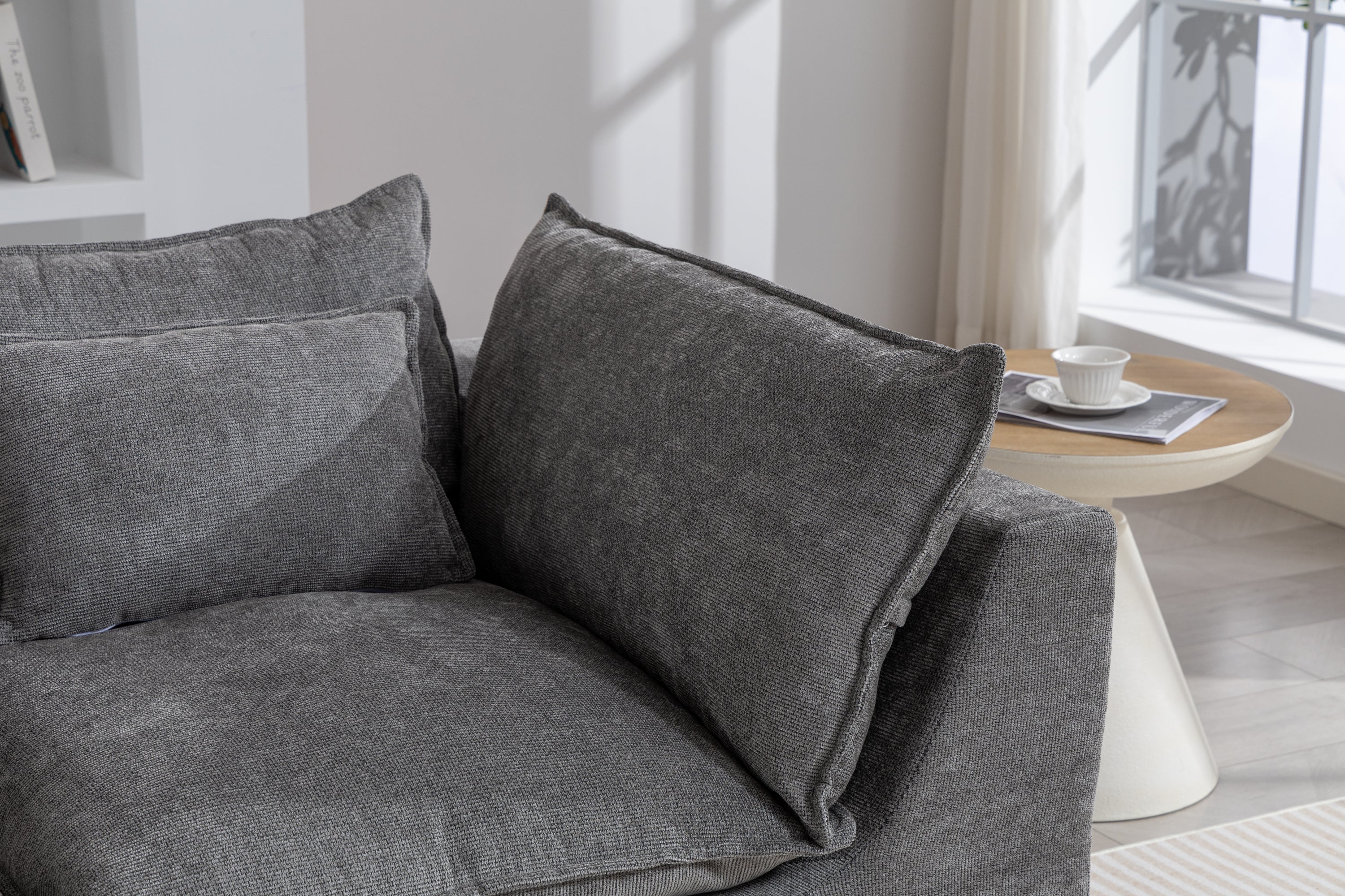 Close-up of the Cloud Couch backrest and armrest cushions in antique grey velvet, styled with a side table.