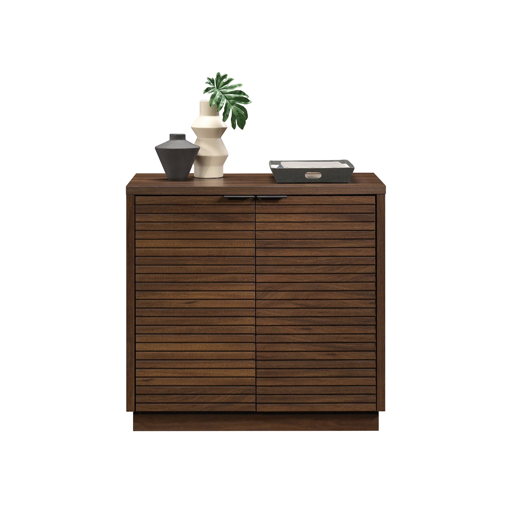Front view of Library Base, Brown finish cabinet with decor on top, showcasing its sleek and compact storage design.