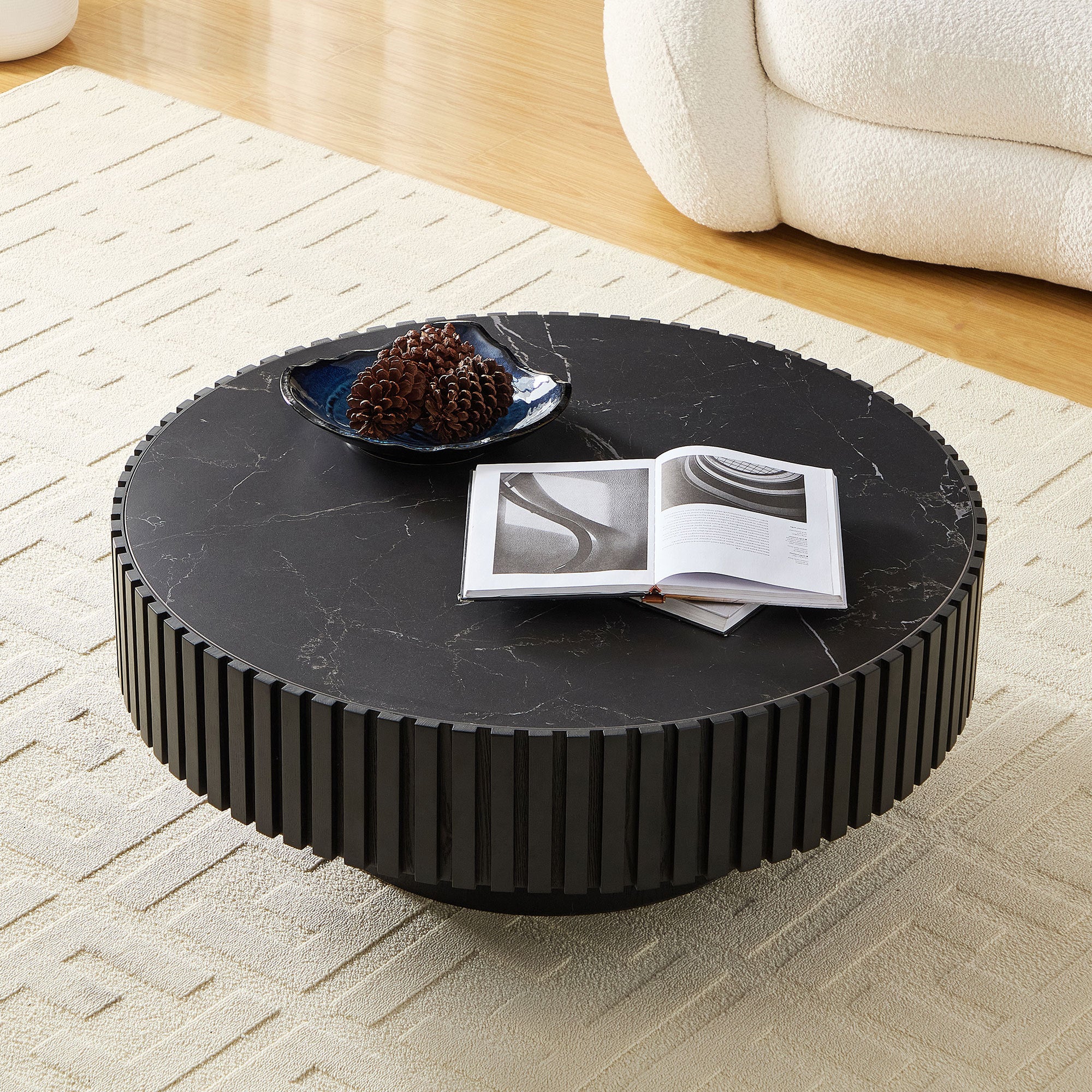 Modern round coffee table with 35.43'' sintered stone top, styled with books and decor in a contemporary living space.