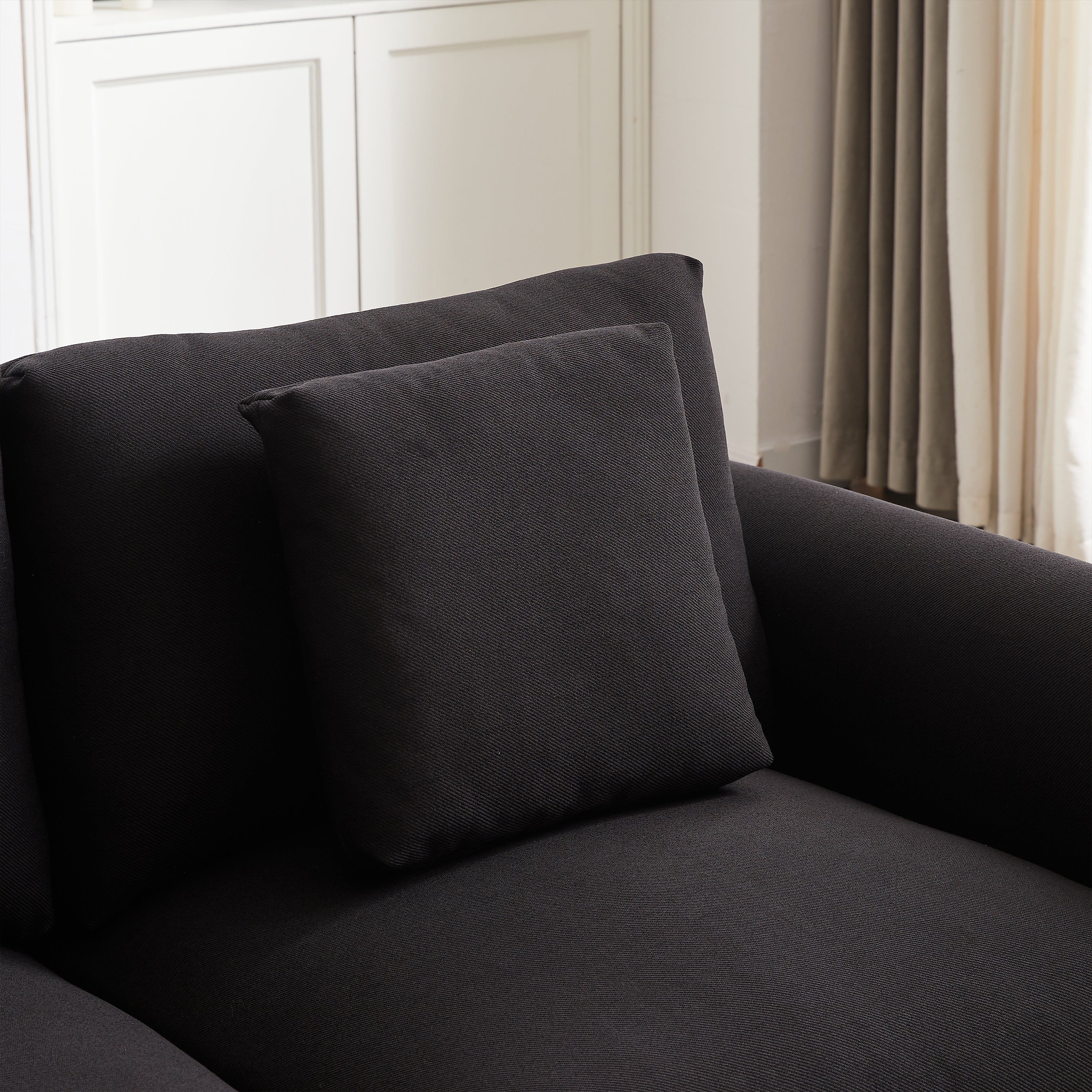 Detail of back cushion and armrest on modular L-shaped sofa with ottoman, showcasing fabric quality and comfort.
