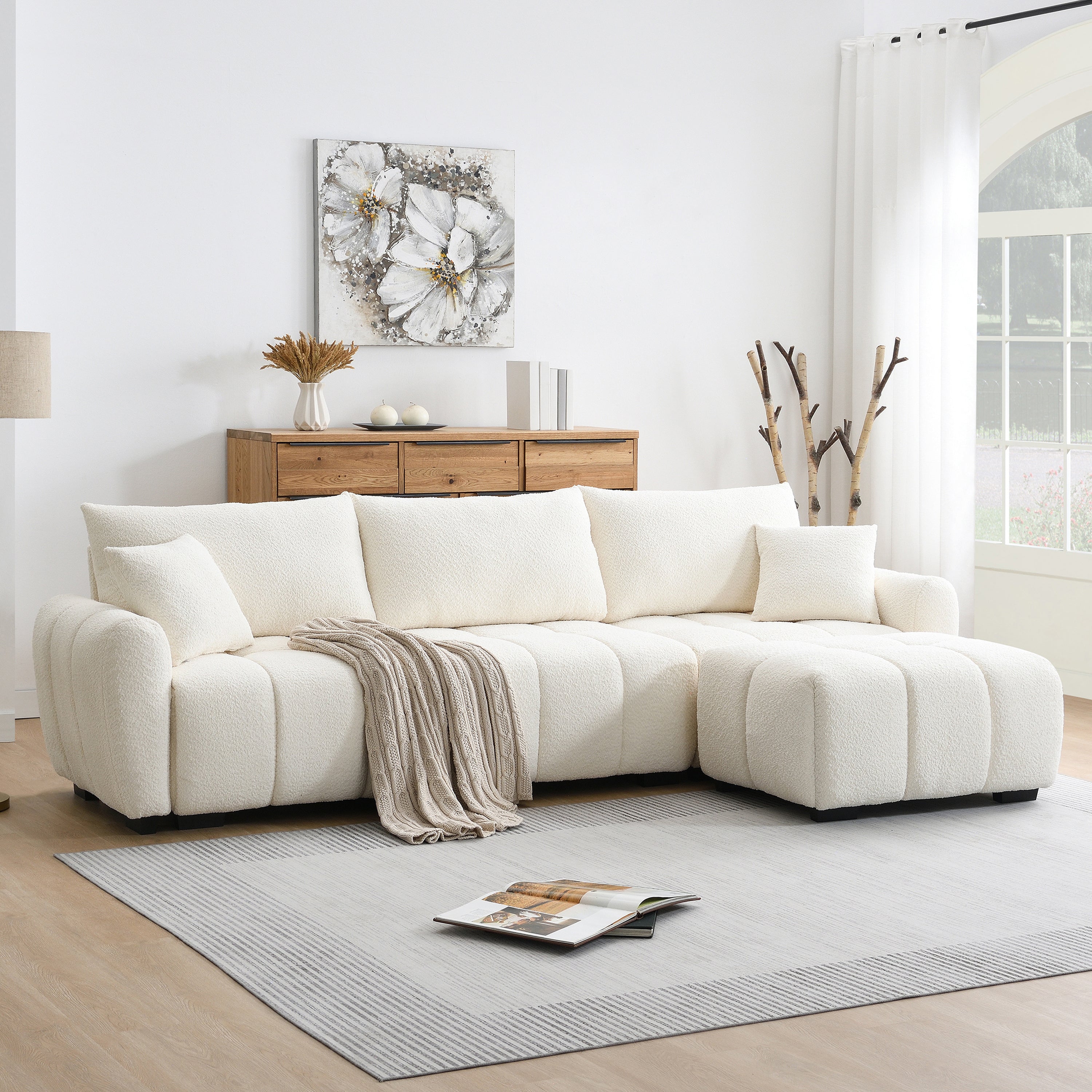 Modular sectional sofa with movable ottoman in boucle fabric, styled in a modern living room with wood accents and neutral tones.